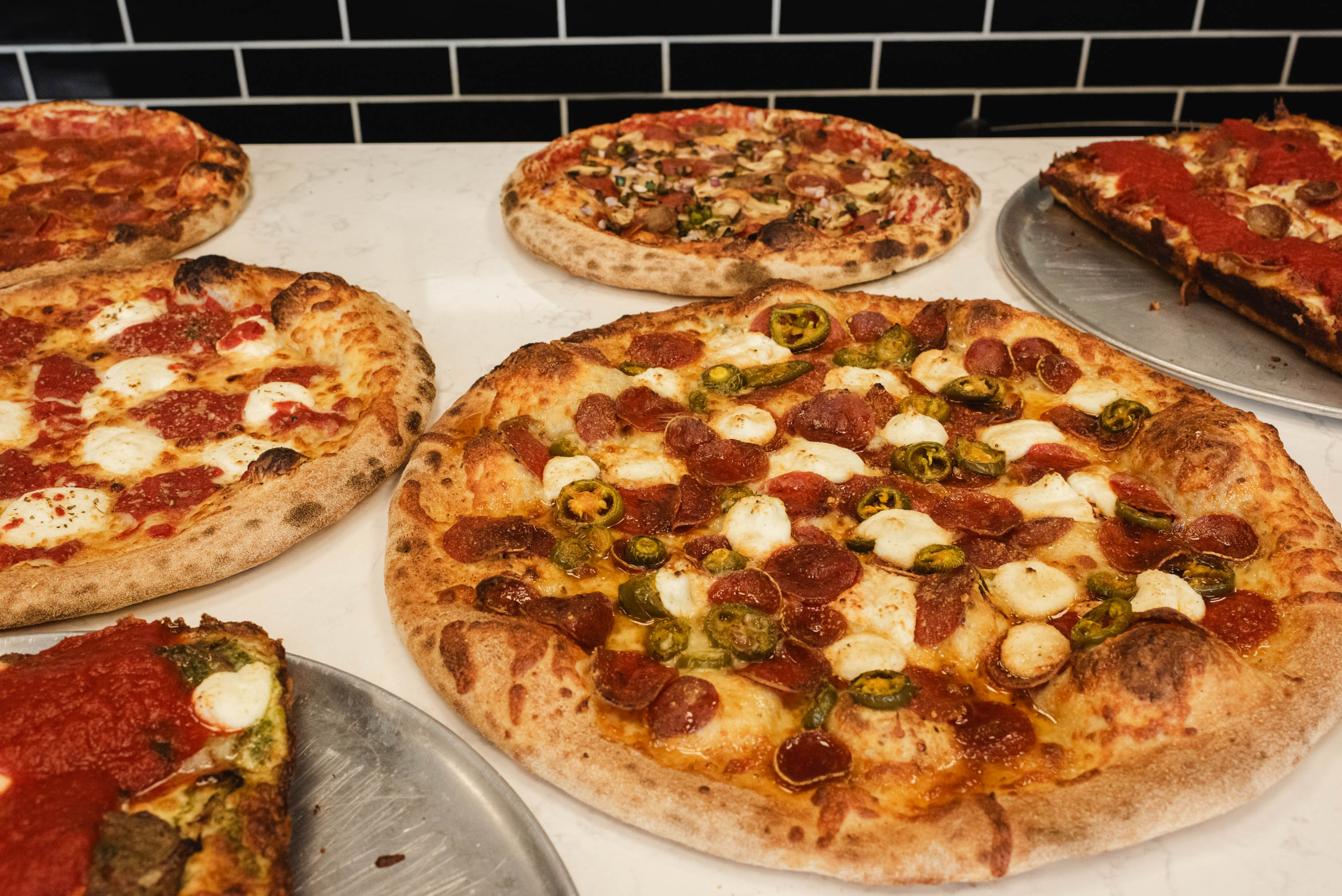 Assorted pizzas served on trays with different toppings
