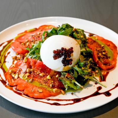 Caprese Salad with mozzarella, tomatoes, basil, pine nuts, and balsamic glaze.