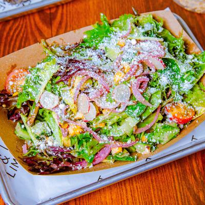 Salad with mixed greens, tomato, pickled red onion, cucumber, cilantro, and dressing.