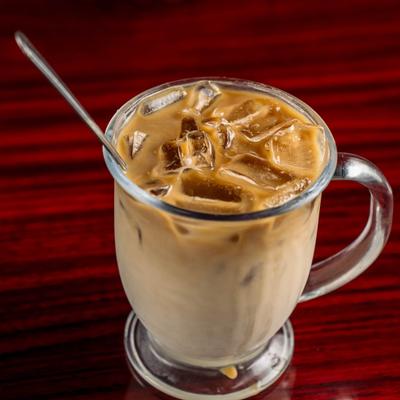 Iced Caramel Latte served in a glass mug with a metal spoon.