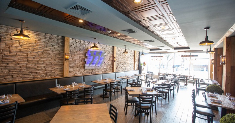 Interior, chairs and tables ready for guests, long leather padded banquette bench
