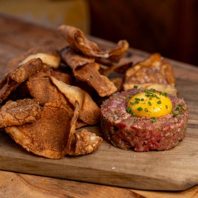 Beef tartare topped with a raw egg yolk served with crispy fried potato chips.