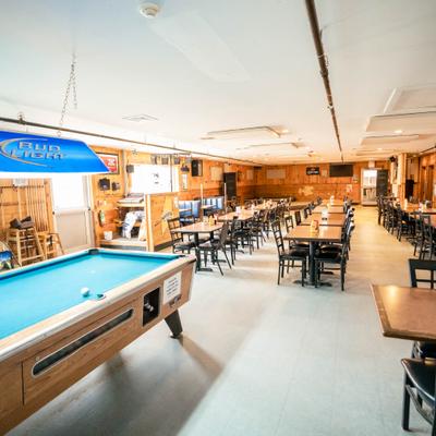 Recreational room with a pool table, blue lamp, and rows of tables with chairs.