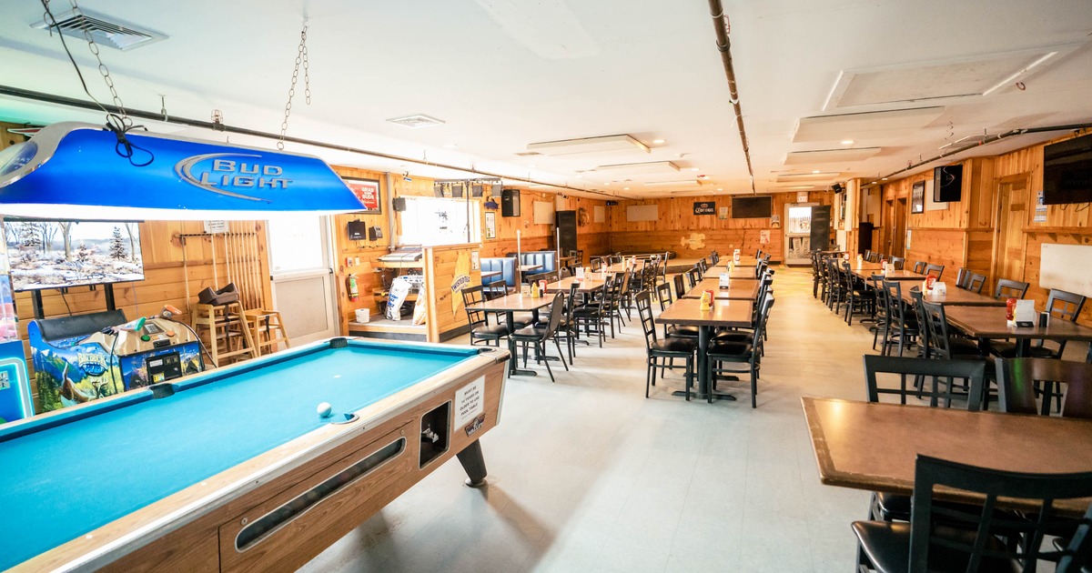 Recreational room with a pool table, blue lamp, and rows of tables with chairs