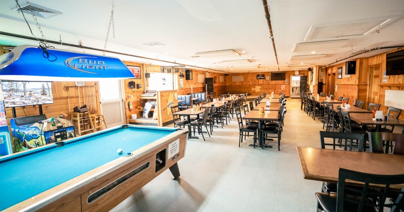 Recreational room with a pool table, blue lamp, and rows of tables with chairs