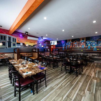 Dining area featuring booths and tables with tableware, mural art on the walls.