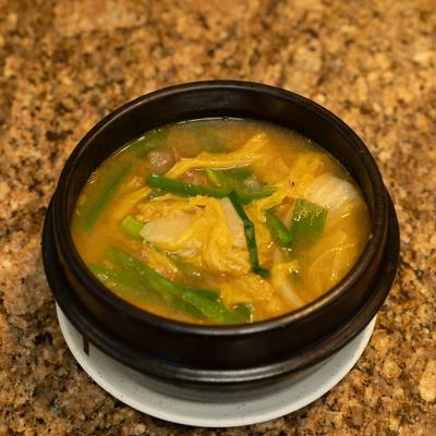 Korean cabbage soup served in a black stone bowl.