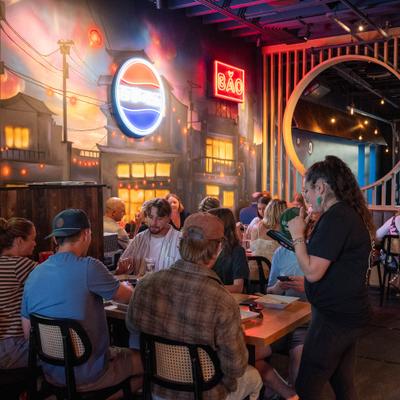 Interior featuring a large neon sign on a mural wall and guests seated at the table.