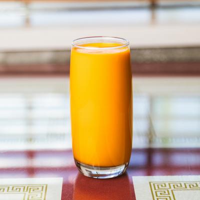Tall glass of mango juice on the table.