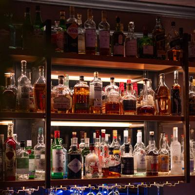 Assorted liquor bottles on illuminated bar shelves.