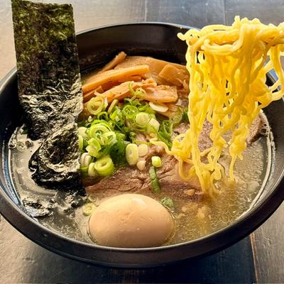 A bowl of ramen with curly noodles being lifted.