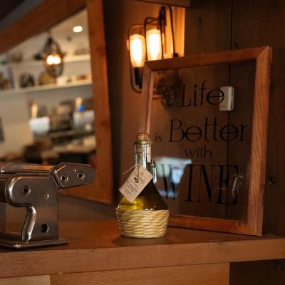 Framed sign reading Life is Better with Wine and a small wine bottle on a shelf.