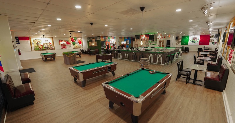 Interior, wide view with pool tables and seating, bar in the background