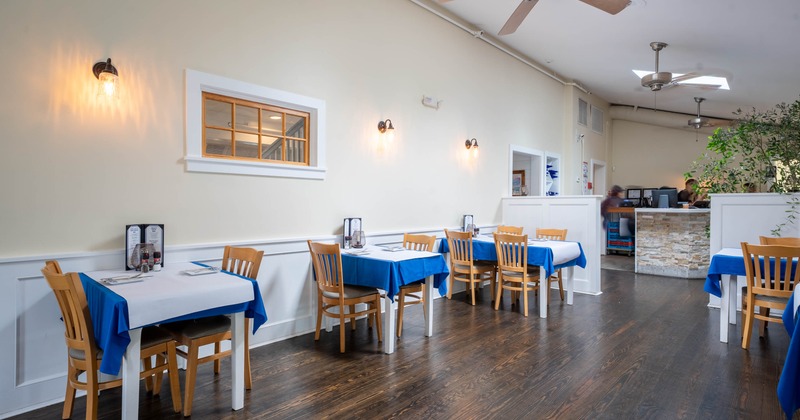 Interior, wooden tables and chairs, blue tablecloths, wall sconces, service counter