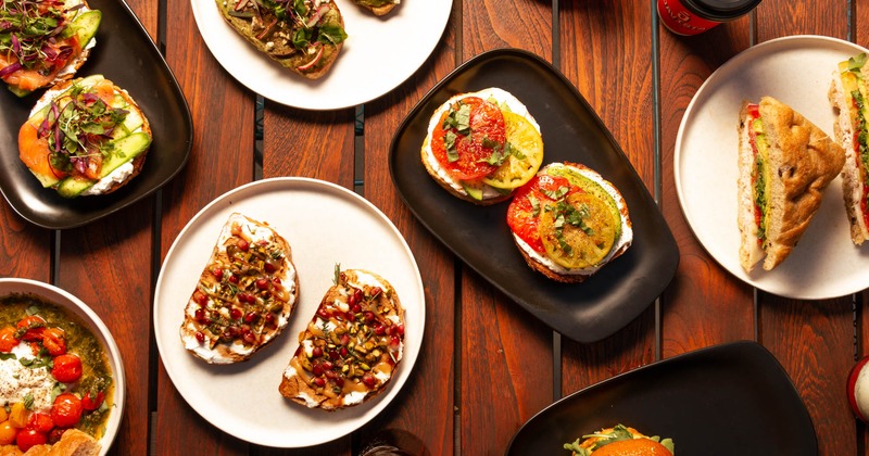 A variety of colorful open-faced sandwiches on different plates