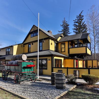 Yellow two-story building with wooden barrels and vintage wagon in the front.