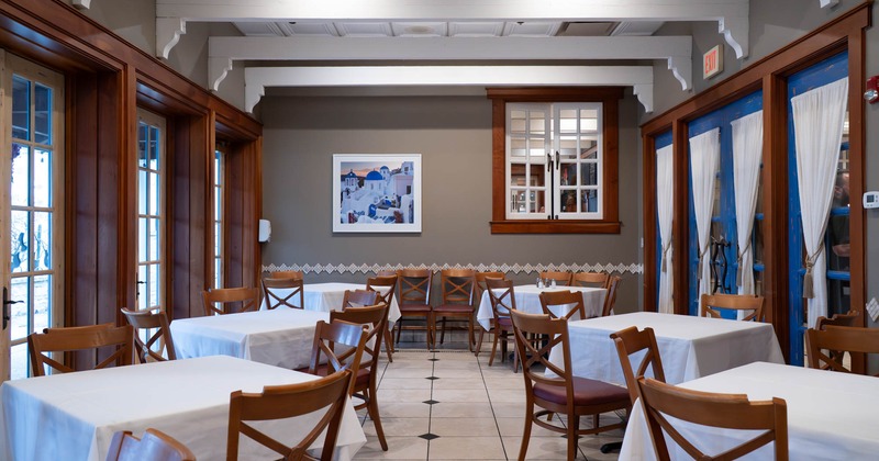 Interior, private dining area, white cloth tables with chairs, tile flooring, Santorini painting
