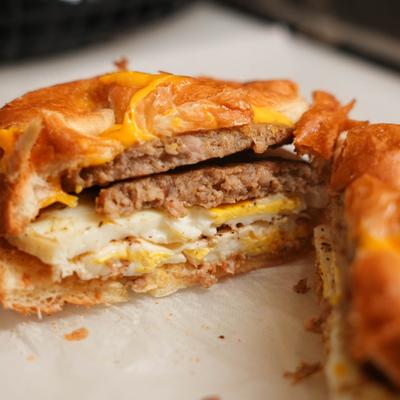 Croissant sandwich with sausage patties, eggs, and cheese.