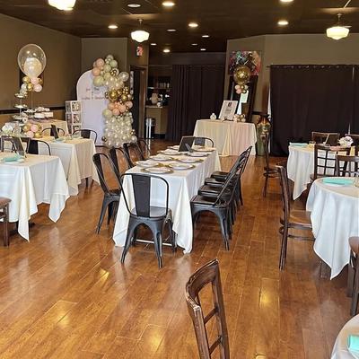 A decorated room for an event features tables set for dining.