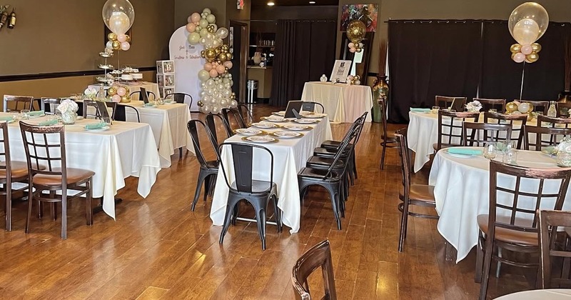 A decorated room for an event features tables set for dining
