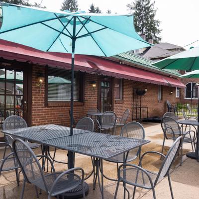 Outdoor patio area featuring a brick building facade, dining tables and umbrellas.
