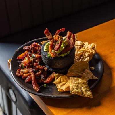 Guacamole served with tortilla chips and fried pork belly.