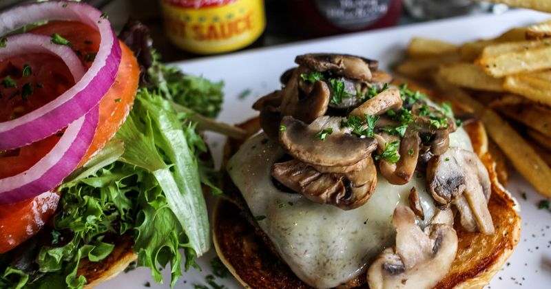 Burger topped with mushrooms, side of fries