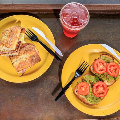 Club sandwich, avocado toast with sliced tomato and a drink, top view.
