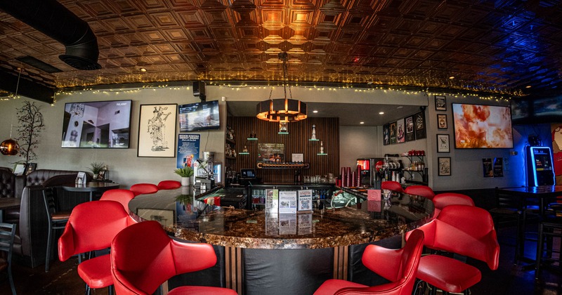 Interior, wide shot of the bar area, marble top bar with red leather stools
