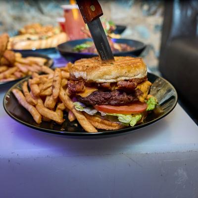 Cheeseburger with fries and other dishes in the background.