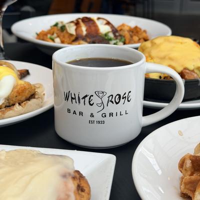 Black coffee served in a branded cup alongside various dishes.