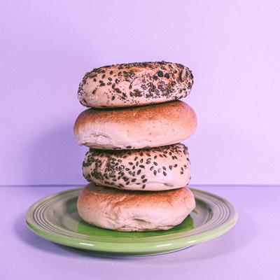 A stack of assorted bagels on a green plate.
