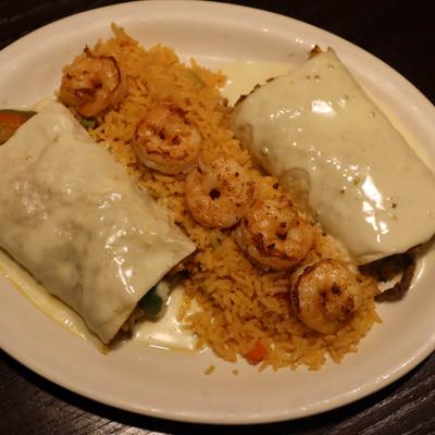 Burrito smothered in cheese sauce, with fried rice, and shrimp.