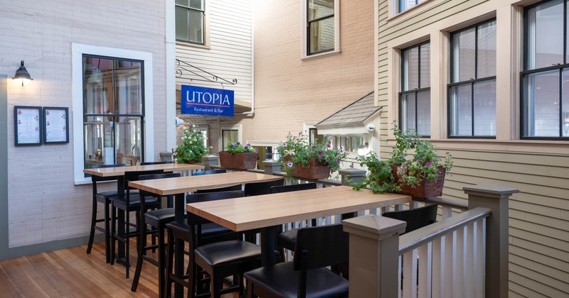 Outdoor seating area with high top tables, black chairs, and planter boxes