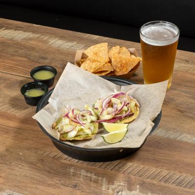 plate with 2 tostadas, chips and salsa and a beer.