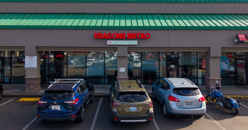 Exterior, front view to restaurant, entrance, sign above, parking lot in front, vehicles