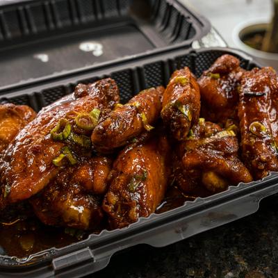 Glazed chicken wings in a takeout conctainer.