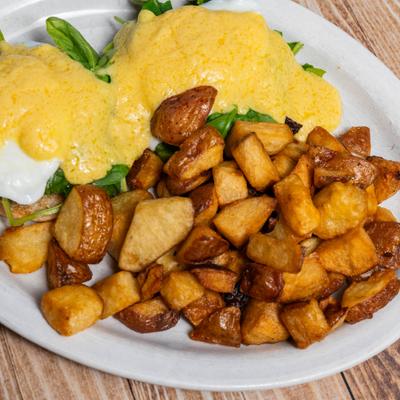 Two poached eggs and spinach on a toasted English muffin with hollandaise sauce.