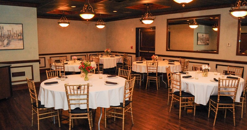 Interior, round tables with white table cloths, tableware and flower decoration