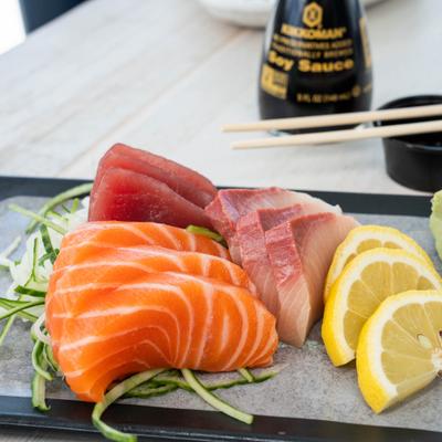 Fresh salmon, tuna, and yellowtail sashimi served with lemon slices and wasabi.