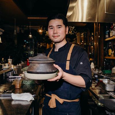 Chef holding a dish in a clay pot.