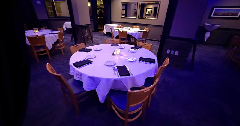 Banquet style room set with tables of six. With black napkins and white table linen.