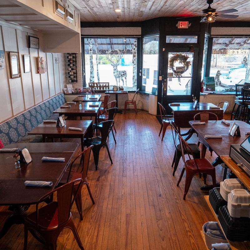 Cozy cafe interior with wooden floors and ceiling, tables, metal chairs, bench seating