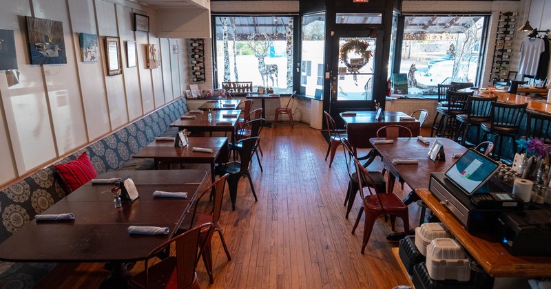 Cozy cafe interior with wooden floors and ceiling, tables, metal chairs, bench seating