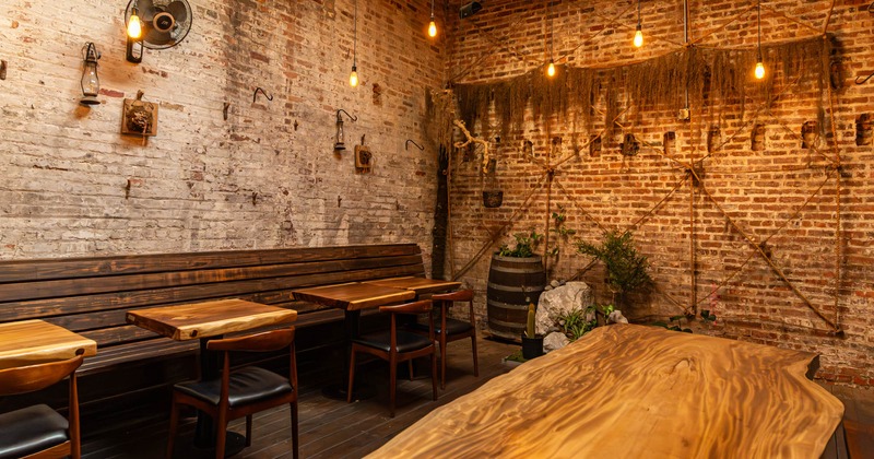 Interior, rustic room with brick walls, wooden tables, benches and decorative plants