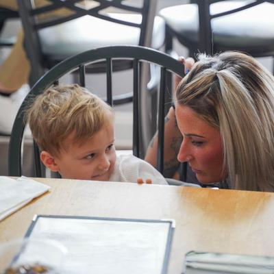 A child and an adult sitting playfully at a table.