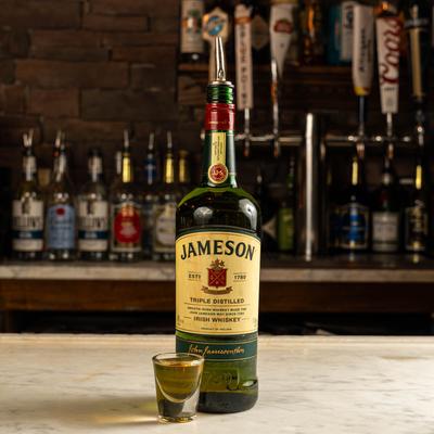 A bottle of Jameson and a shot on a bar counter.