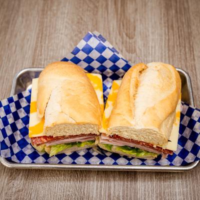 A halved sub sandwich with salami, lettuce, and cheese.