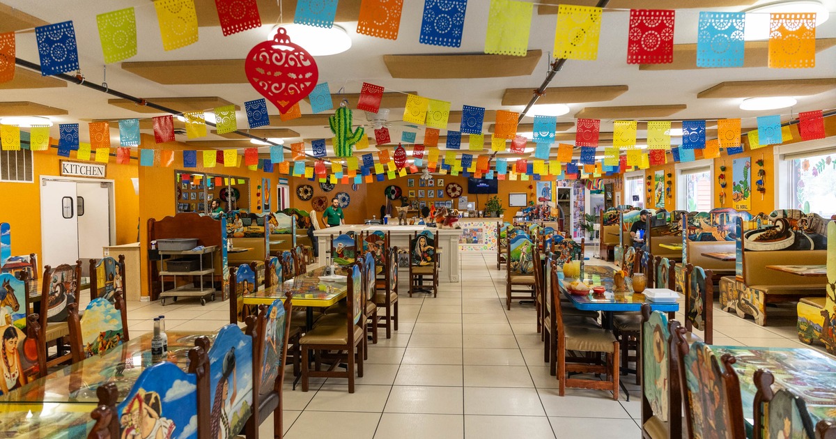 Colorful Mexican restaurant interior with papel picado banners and hand painted furniture