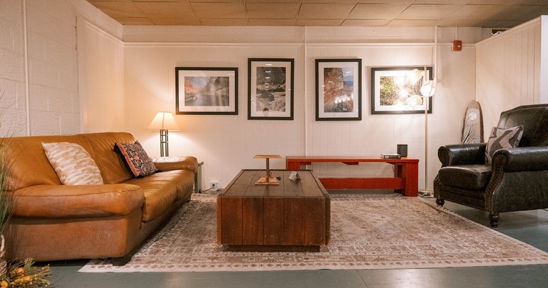 Interior - tan leather couch, black armchair, wooden coffee table and framed photographs on the wall